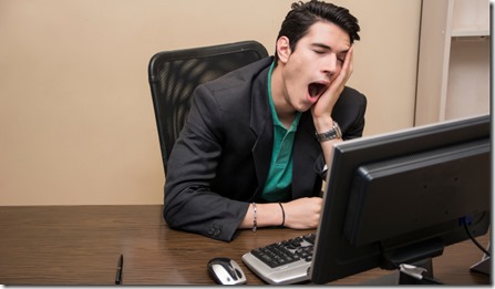 Tired bored young businessman sitting in office yawning